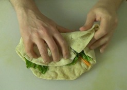 folding the edge of the pita over the fillings